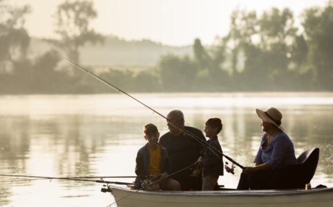 Family of four fishing from a boat on a calm lake in Louisiana at sunrise.