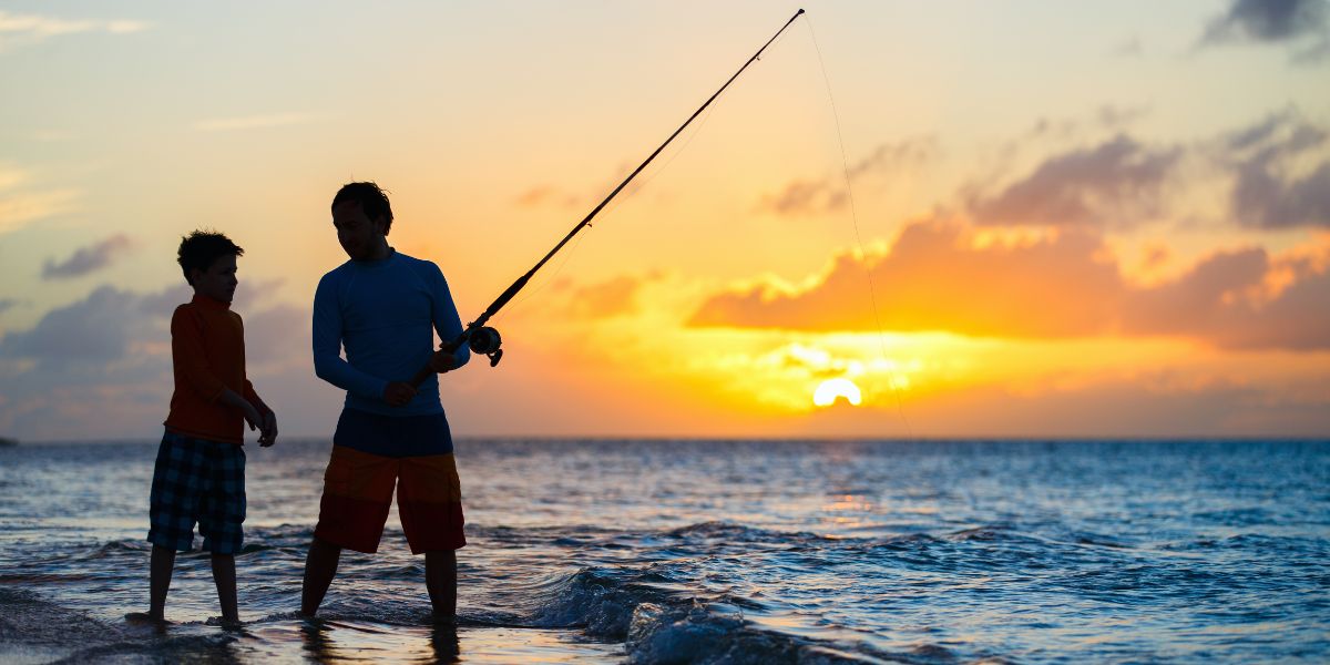 Father and son fishing in the ocean at sunset on a Louisiana beach.