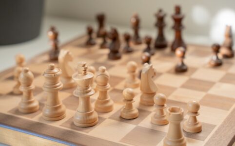 Hand makes a strategic move with a chess piece on a minimalist, modern chessboard, symbolizing advanced SEO strategy and c...
