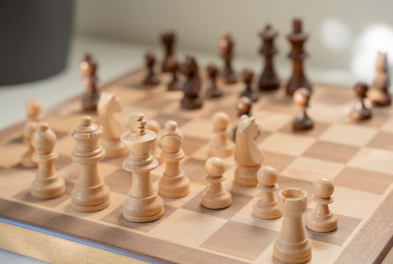 Hand makes a strategic move with a chess piece on a minimalist, modern chessboard, symbolizing advanced SEO strategy and c...