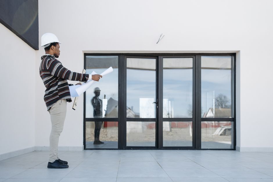 A hopeful couple reviews architectural blueprints in a bright, modern living room, planning their home purchase with new financial advantages.